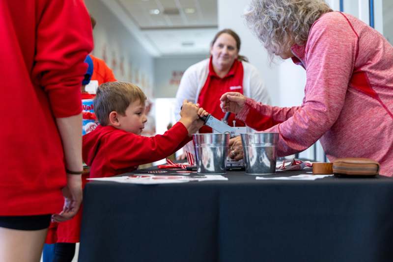 a boy cutting a knife with a woman in red shirts