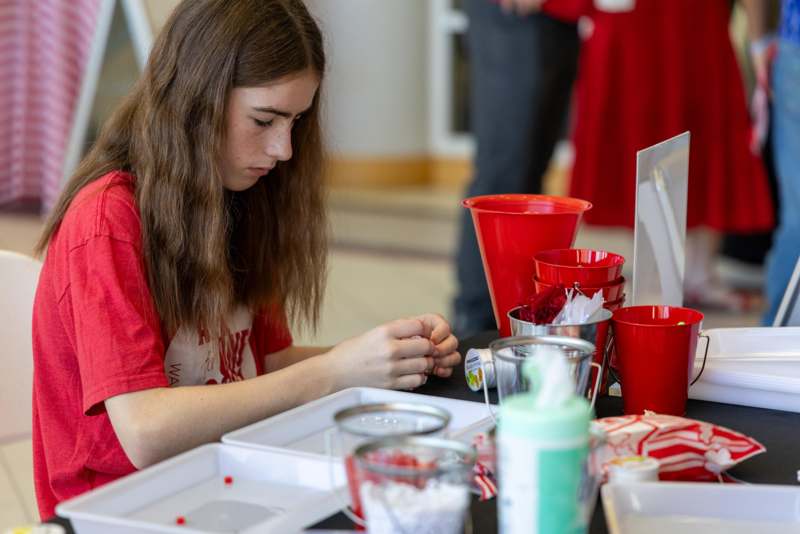 a girl sitting at a table with red cups and red cups