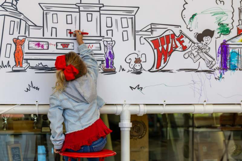 a girl drawing on a white board