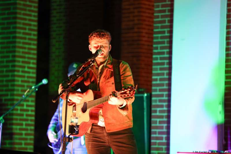 a man playing guitar and singing on stage