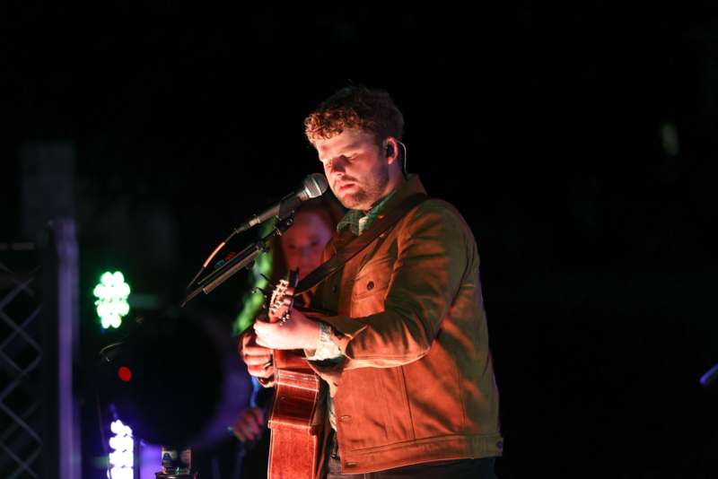 a man playing guitar and singing into a microphone