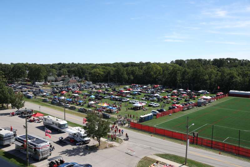 a parking lot with cars and tents and a field with trees