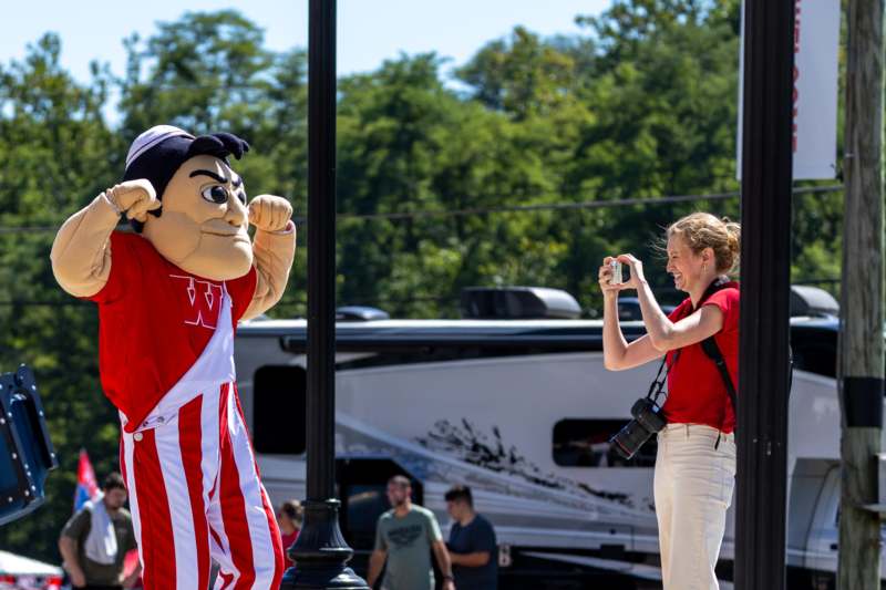 a woman taking a picture of a person in a mascot garment