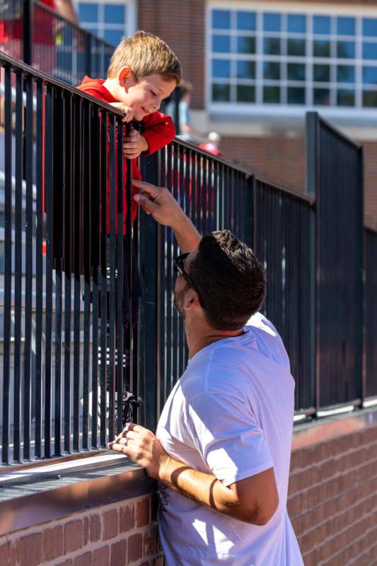 a man looking at a child on a fence