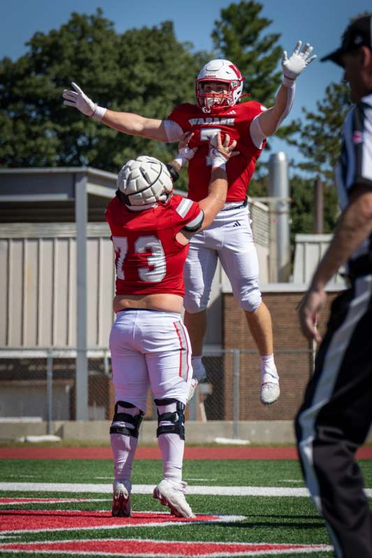 a football player jumping over another football player