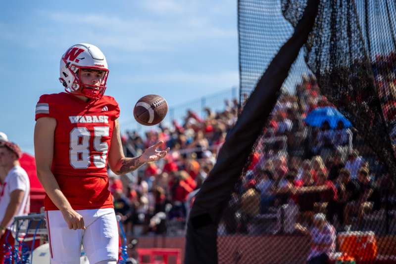 a football player in a red uniform throwing a football