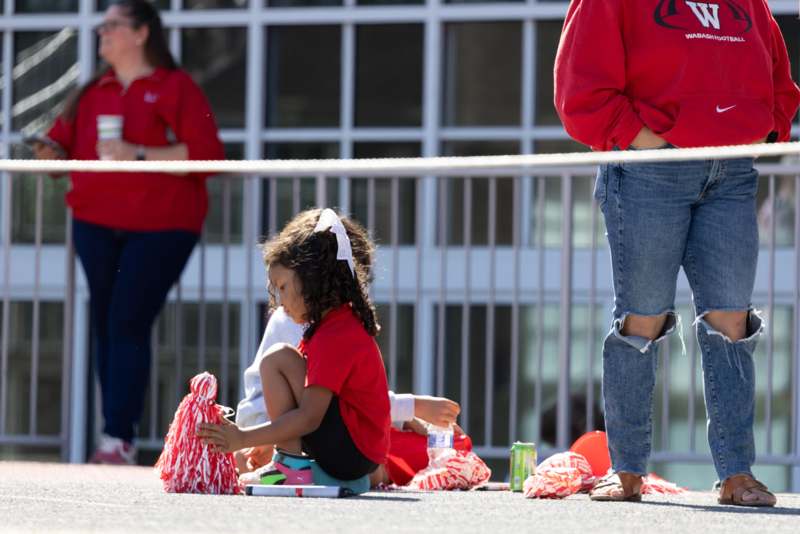 a girl sitting on the ground with pom poms