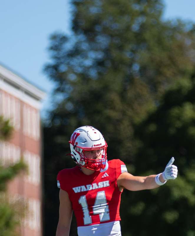 a football player wearing a red uniform and giving a thumbs up