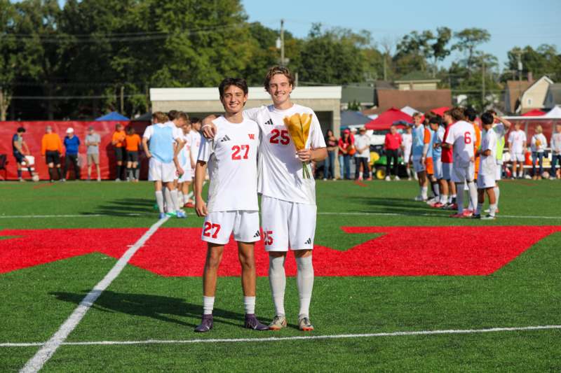 two boys in white uniforms on a field
