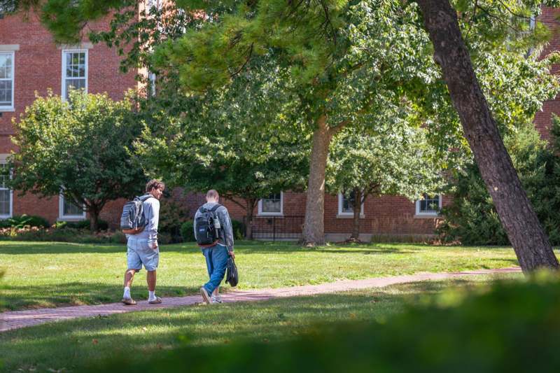 two men walking on a sidewalk