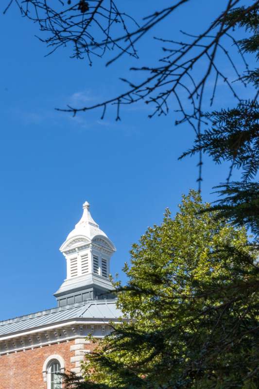 a white building with a steeple and trees