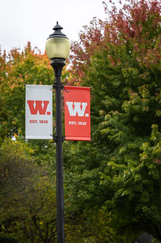 a lamp post with a sign and a red and white banner
