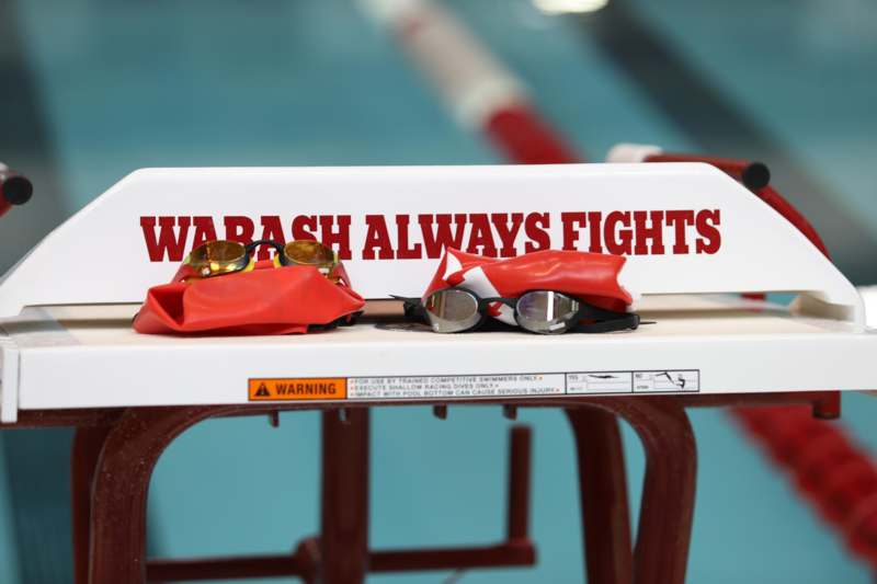 a swimming pool bench with goggles and a red bag