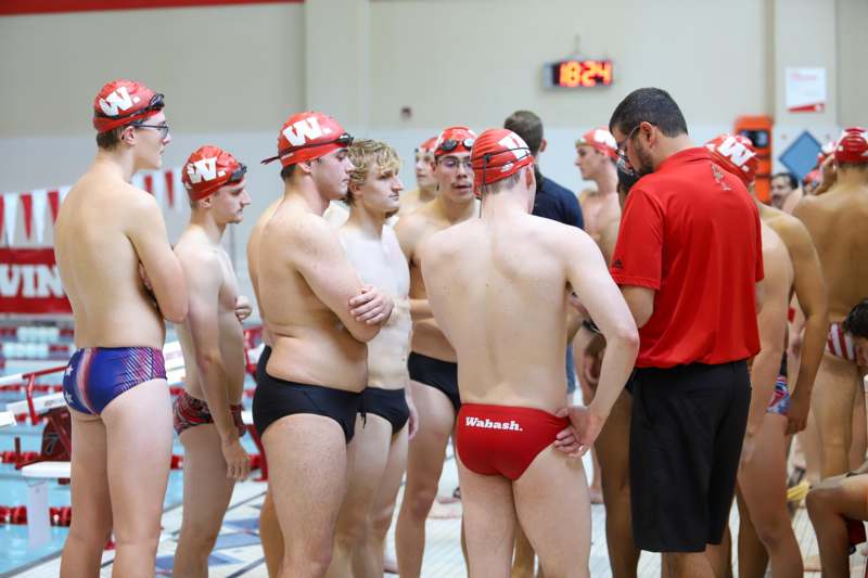 a group of men in swimsuits standing in a pool