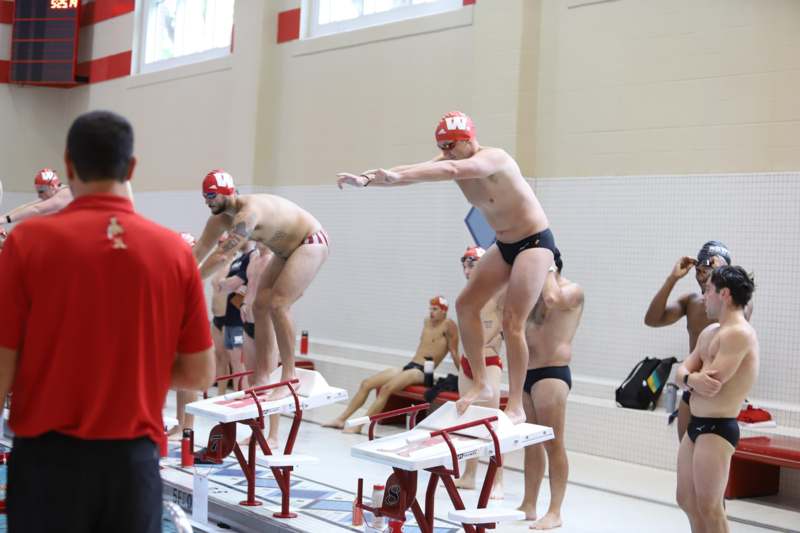 a group of men in swim caps standing on diving boards