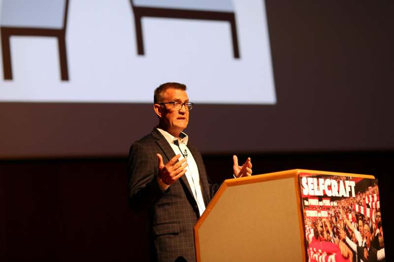 a man standing at a podium with his hands up