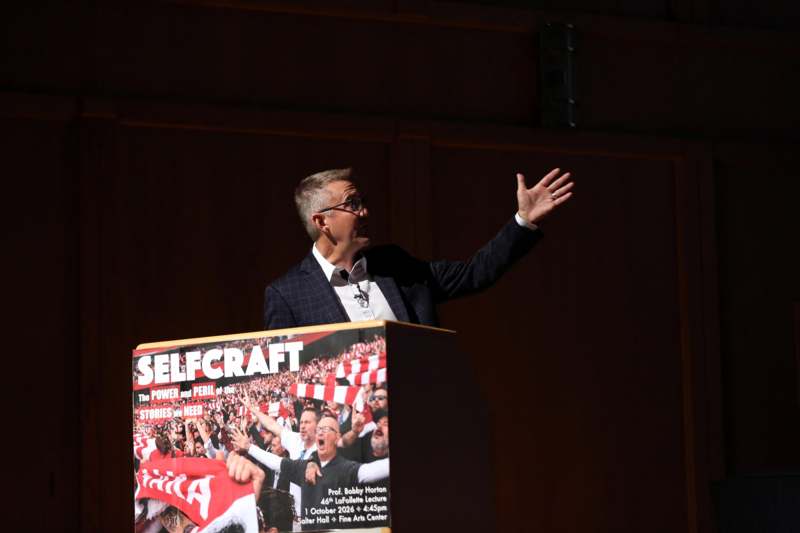 a man standing at a podium with his hand up