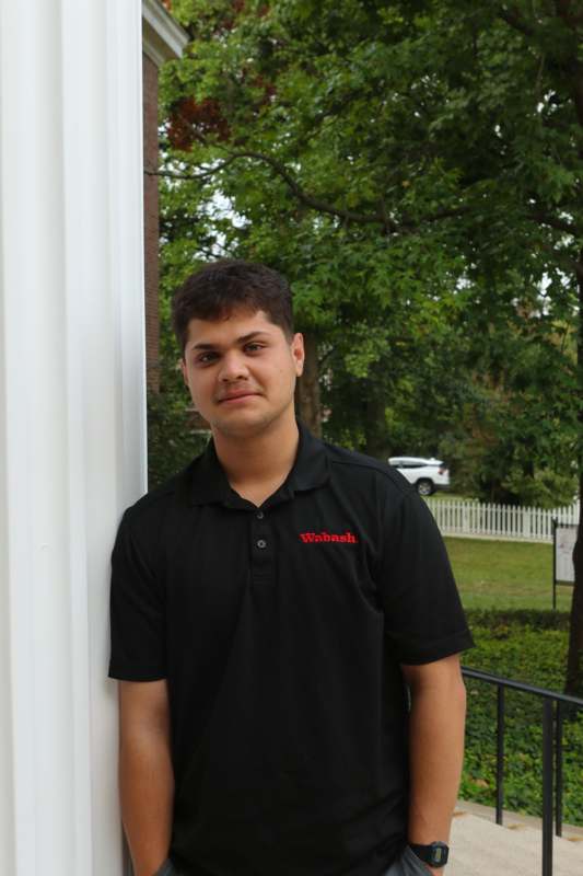 a man standing next to a white column