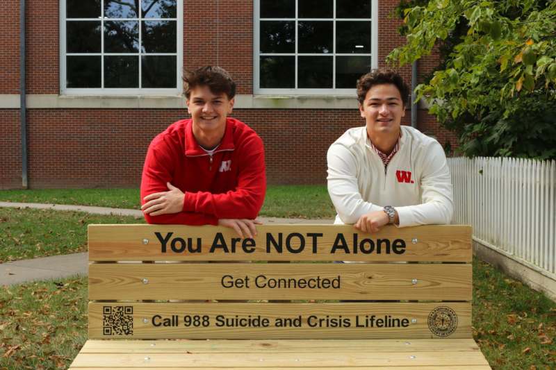 two men posing for a picture on a bench