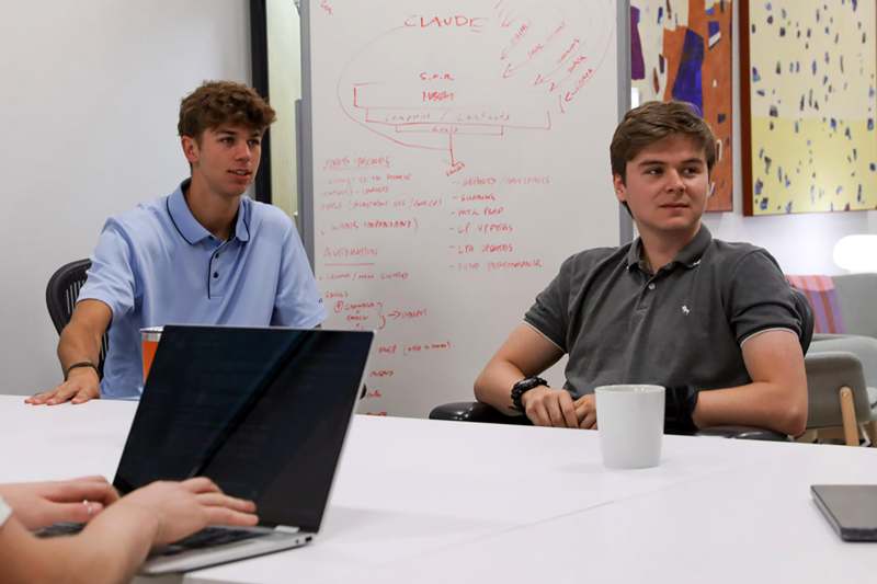 a group of men sitting at a table with a laptop