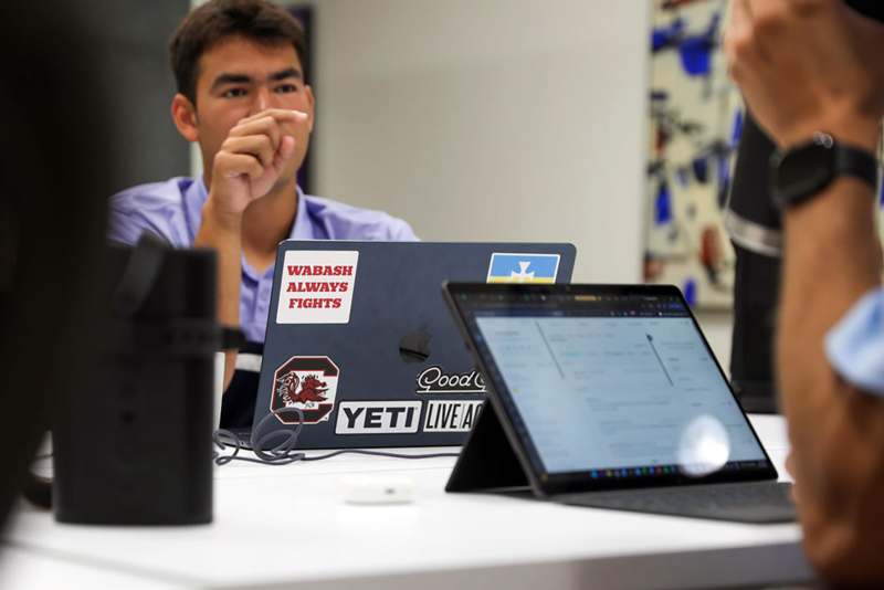 a man sitting at a table with a laptop and a camera