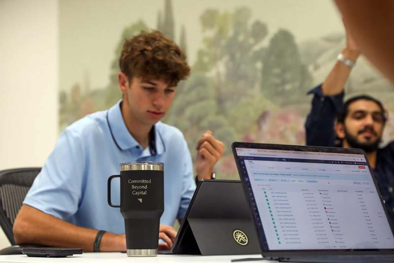 a man sitting at a table with a laptop and a cup