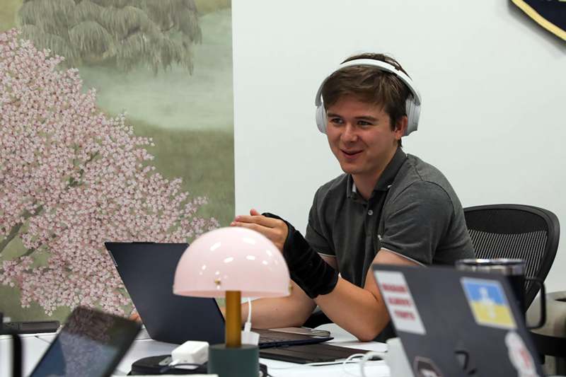 a man wearing headphones and sitting at a desk with a laptop