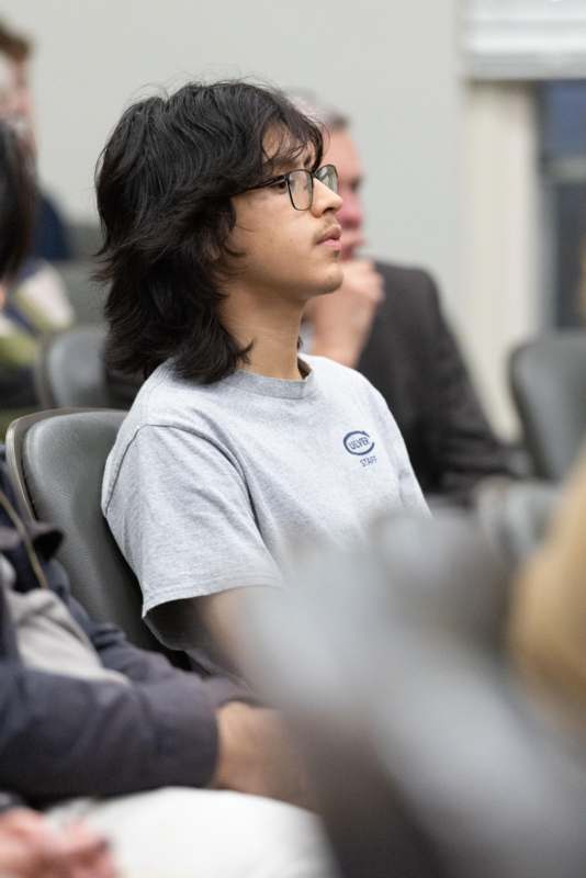 a man in glasses looking away from other people