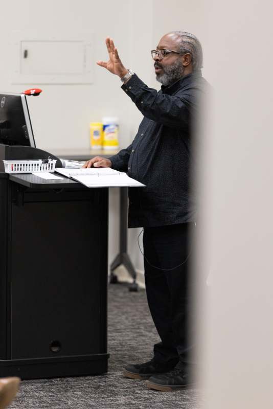 a man standing at a desk with his hand up