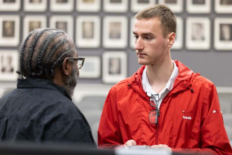 a man in a red jacket talking to another man