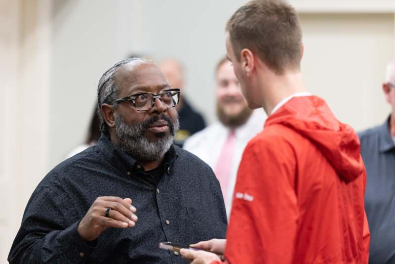 a man in a black shirt talking to a young man