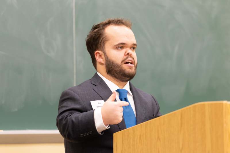 a man standing at a podium pointing at something