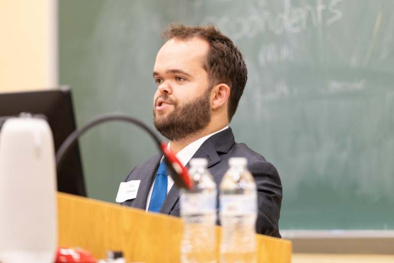 a man in a suit speaking at a podium
