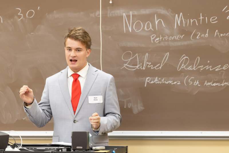 a man in a suit and tie standing in front of a chalkboard
