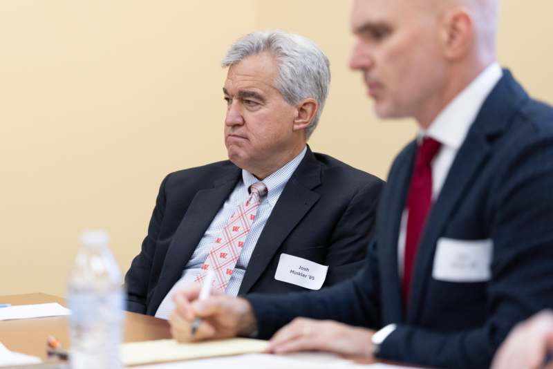 a man in suit sitting at a table with another man in suit