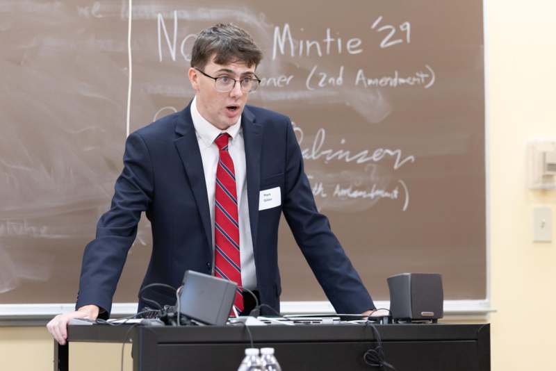 a man in a suit standing in front of a chalkboard
