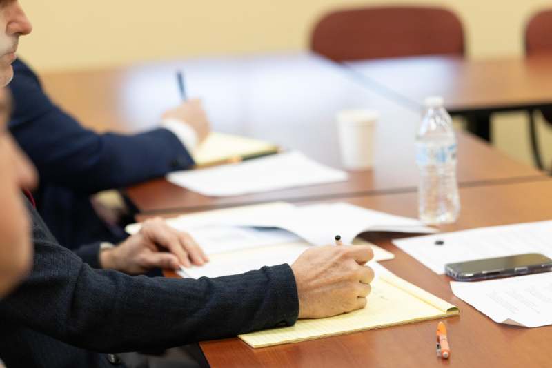 a group of people sitting at a table writing on papers