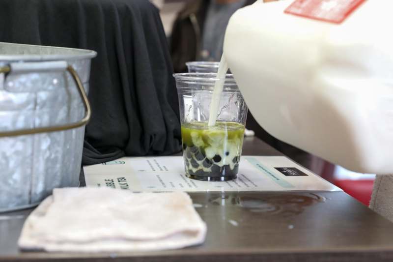 a pouring milk into a glass of bubble tea