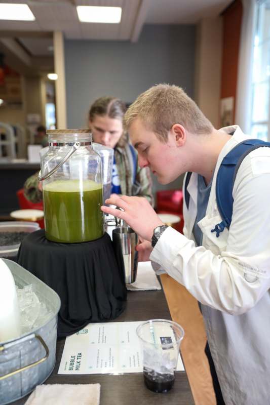 a man looking at a green liquid in a container
